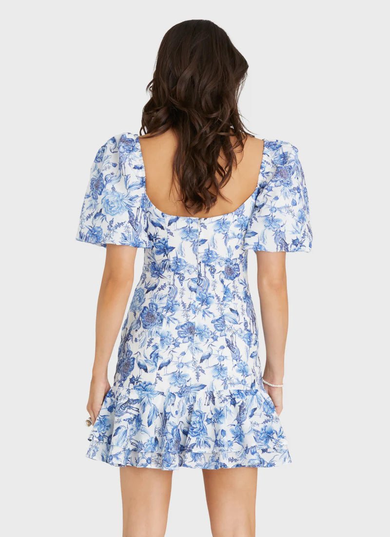 Rear view of a model wearing Aqua Blu Australia Azalea Scarlet Mini Dress in blue floral print with puff sleeves and square neckline.