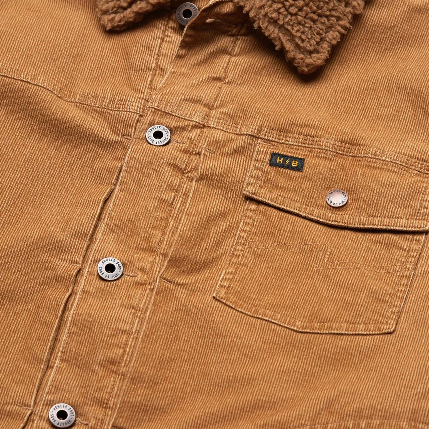 Close-up of Howler Brother's Fuzzy Depot Corduroy Jacket with buttons and a pocket, featuring their brand label.
