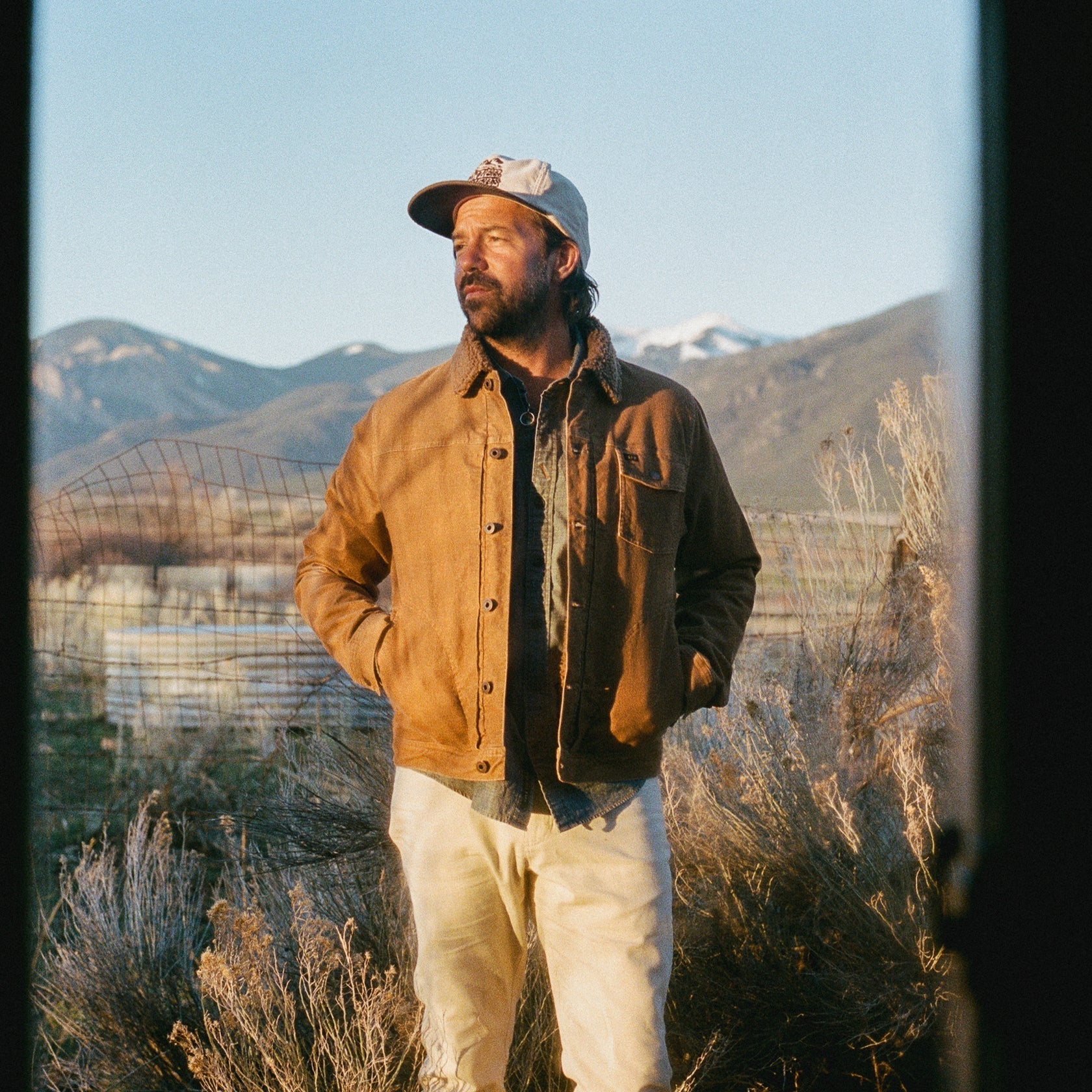 Man wearing a the Howler Fuzzy Depot Jacket in Duck Brown Cord standing in a landscape with mountains in the background
