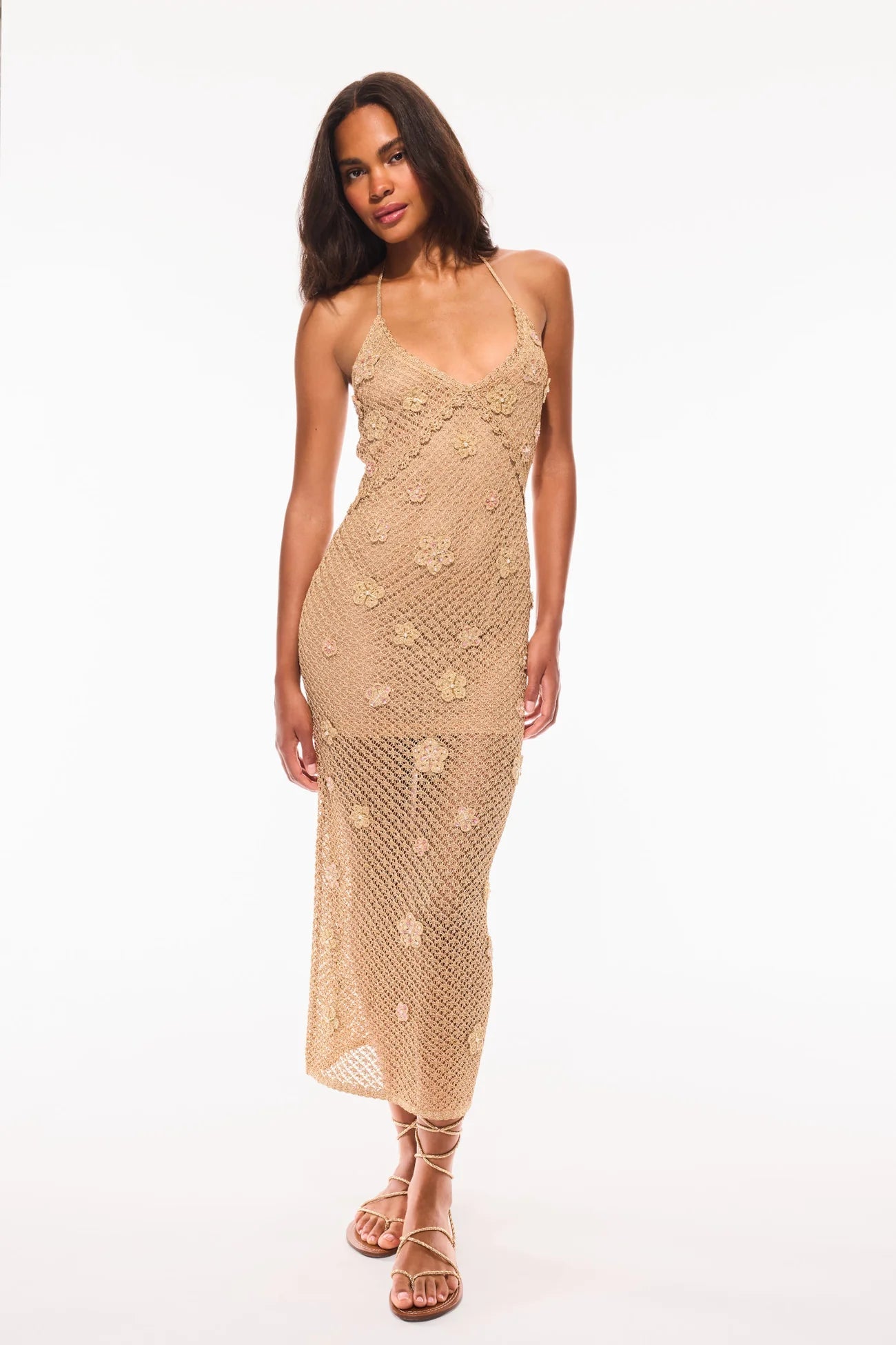 Full length front view of a gold crochet midi dress by LoveShackFancy, styled for a luxury beach vacation or tropical event.