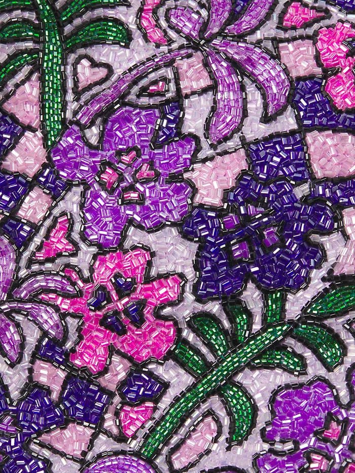 Detailed texture shot of hand-embroidered floral motif on a luxury purple swimsuit by Oceanus, featuring sparkling beadwork.
