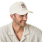 Front view of the Brixton Aces men's snapback hat in off-white organic cotton, featuring a high-profile crown and red and black playing card embroidery.