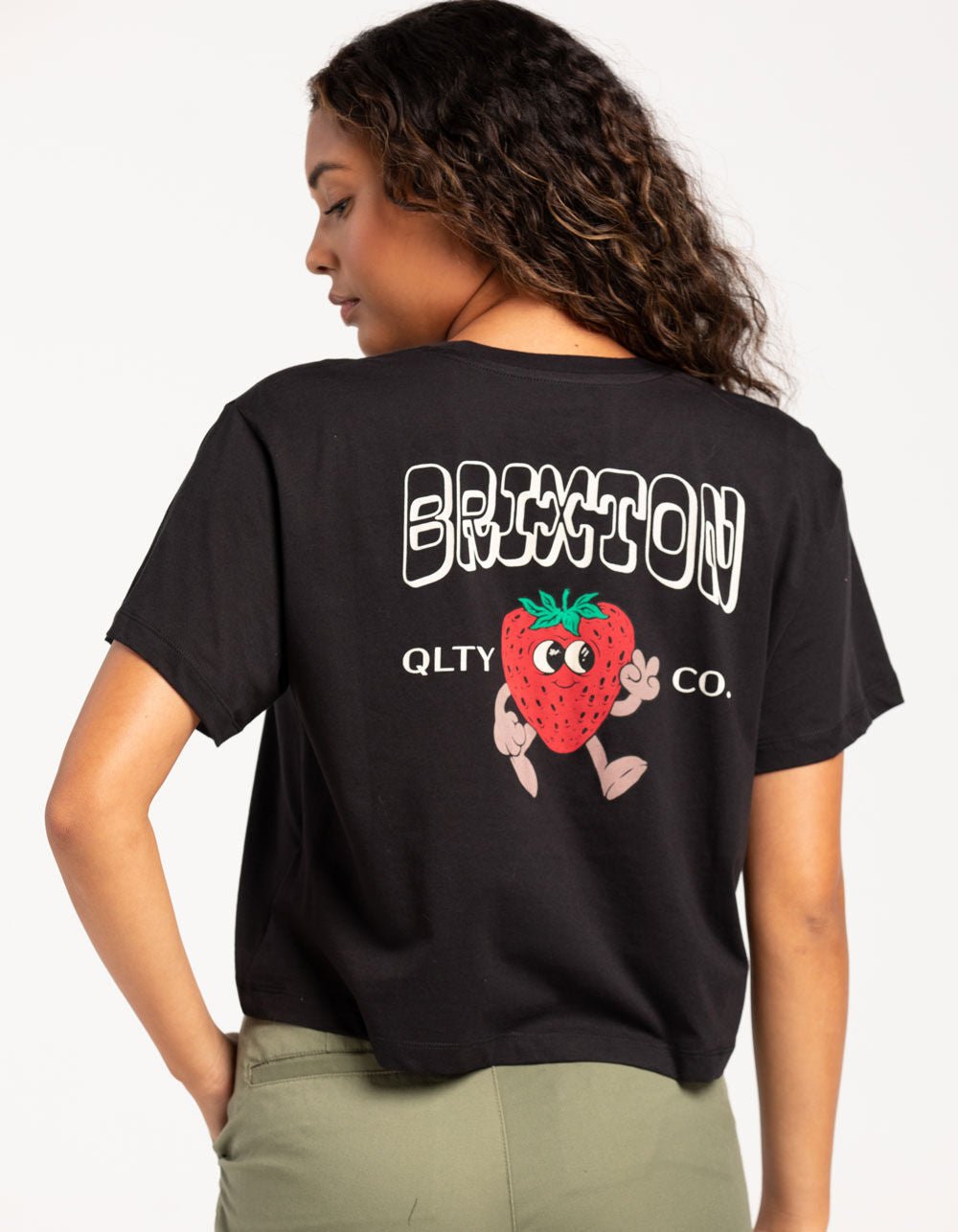 Woman wearing the Brixton Short Cake Boxy tee (cropped t-shirt with a strawberry graphic and 'Brixton' branding on the back).