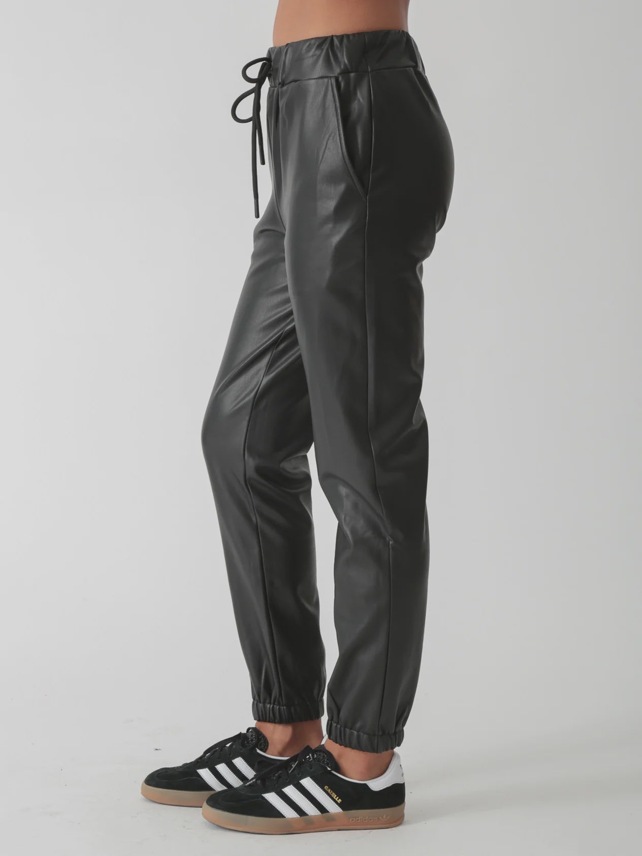 Side view of Electric & Rose Downtown Vegan Leather Joggers in Onyx—tapered faux leather pants with an elastic drawstring waist.