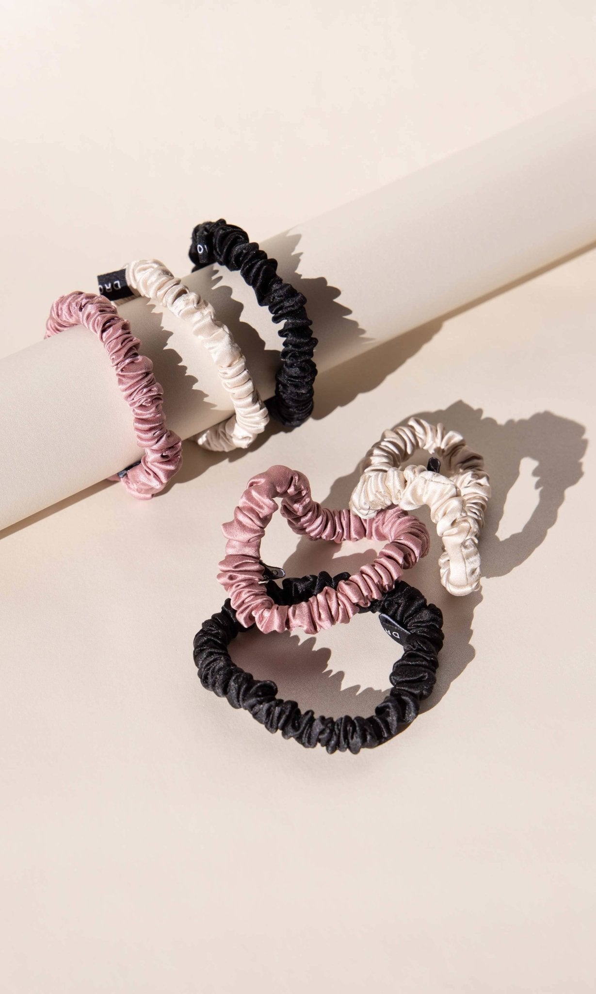 Set of Drowsy Silk scrunchies in pink, black, and gold.