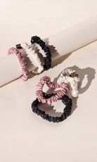 Set of Drowsy Silk scrunchies in pink, black, and gold.