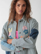 Model wearing the Electric & Rose Indigo Stripe Embroidered Chore Jacket, featuring dark blue denim-style elbow patches and floral embroidery on the chest.