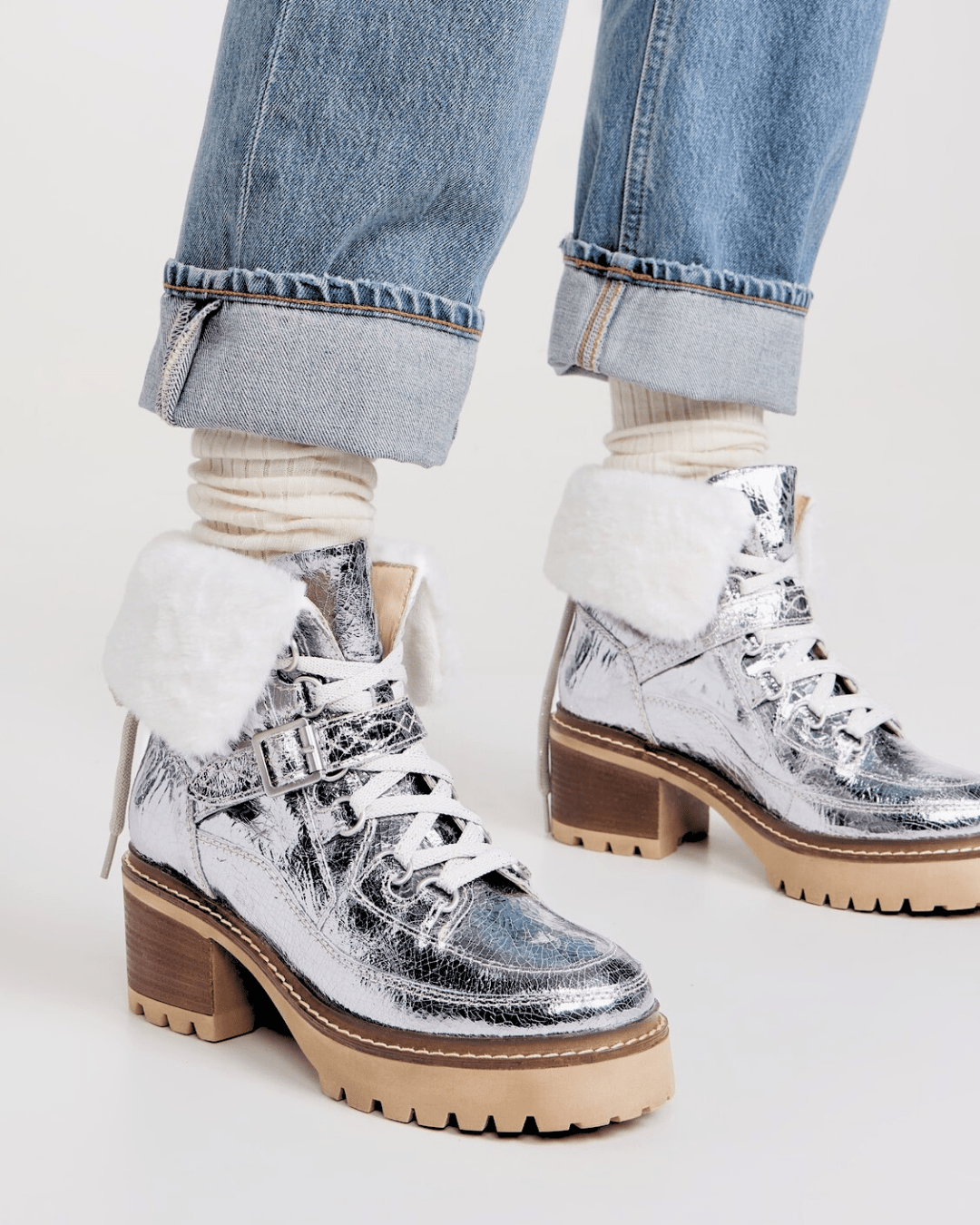 Side profile of a woman wearing Pale Pewter metallic leather boots with faux shearling trim and a chunky lug sole.