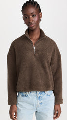 Clos up view of a model wearing the LNA Sherpa half-zip in brown sherpa styled light wash jeans.