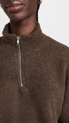 Close up of the mock neck and zipper detail of a model wearing the LNA Sherpa half-zip in brown sherpa.