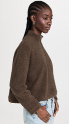 Side profile of a model wearing the LNA Sherpa half-zip in brown sherpa styled light wash jeans.