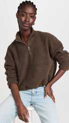Brown Sherpa half-zip by LNA styled with cinched sleeves on woman with light wash jeans.