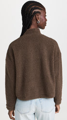 Rear view of a model wearing the LNA Sherpa half-zip in brown sherpa styled light wash jeans.