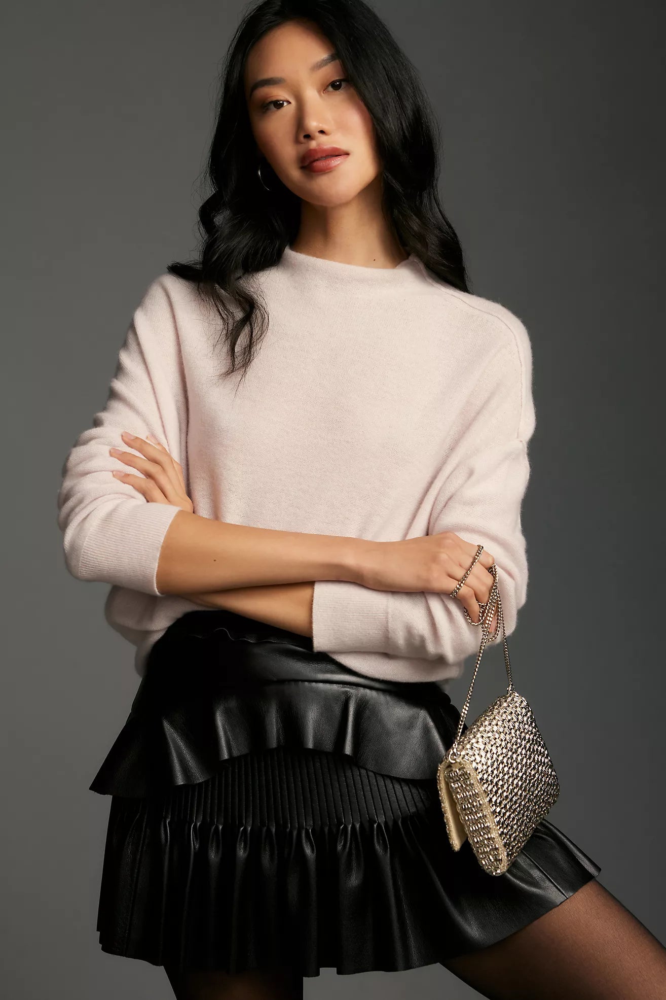 Woman wearing a sweater and the LoveShackFancy black faux leather Eli Skirt