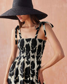 Close-up of the Omika Lana Maxi Dress in Emma Mussel print, showing the black and white hand-painted floral pattern, comfortable smocked bodice, and adjustable self-tie shoulder straps.