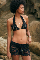 Model wearing the PQ Swim Midnight Lace Halter Bikini Top and matching Lexi Lace Shorts with scalloped edges.