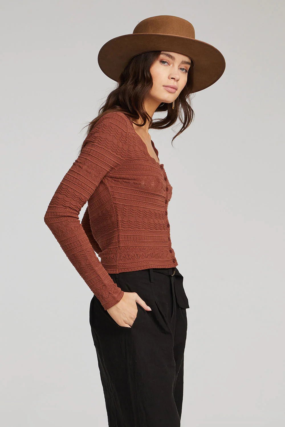 Profile view of the Saltwater Luxe Wilfred Sweater in Pecan, styled with a wide-brim hat and black trousers on a fit model.
